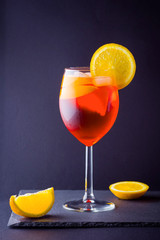 Cocktail aperol spritz on dark background. Summer alcohol cocktail with orange slices. Italian cocktail aperol spritz on slate board. Trendy beverage