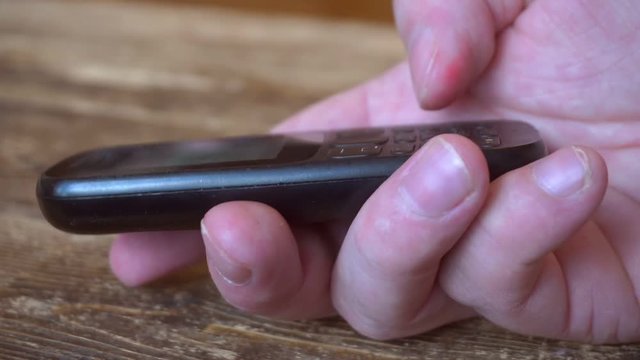 outdated push button mobile phone in hand.finger presses the phone buttons.close-up