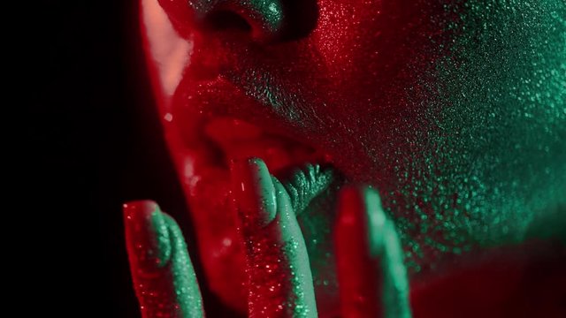 Fashion portrait of woman touching her lips with fingertips in glitter and in neon lights in 80's style, video portrait with green and red mixed neon on dark background, Shot on blackmagic 422 prores