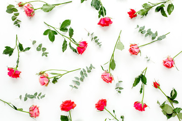 Floral pattern made of red roses and eucalyptus branches on white background. Valentine's background. Floral pattern. Flat lay, top view. 