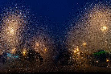 city street light , view through transparent glass with fog from water drops in dark blue night , has rainbow color and look like many stars in galaxy space