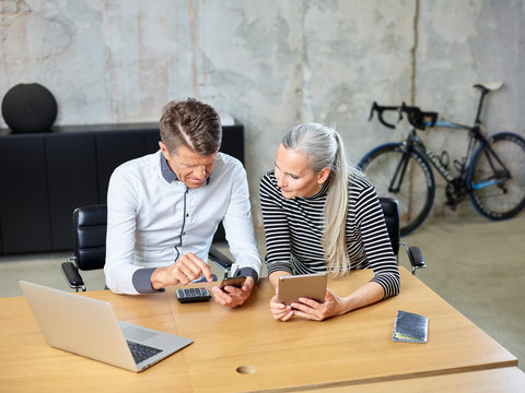 Businessman and businesswoman with cell phone and tablet in office