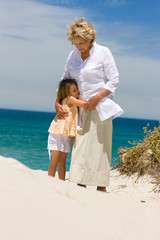 Grand mother and grand daughter hugging on the beach