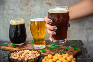 tres tipos de cerveza rubia, roja y negra, sobre una tabla de madera, con mani, fondo metalico. festejando san patricio