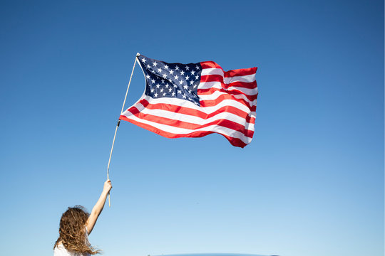 Girl holding American flag under blue sky