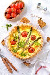 Tart pie with cheese, asparagus, bacon and cherry tomatoes. Top view.