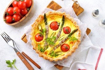 Tart pie with cheese, asparagus, bacon and cherry tomatoes. Top view.
