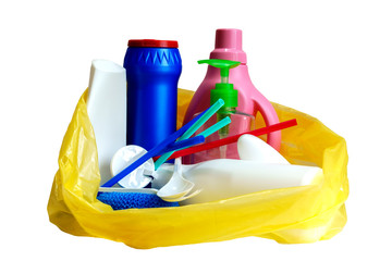 multi-colored empty plastic bottles and utensils in yellow trash bag, isolated on white background
