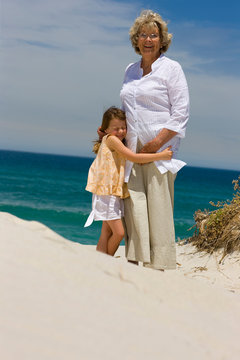 Grand Mother And Grand Daughter Hugging On The Beach