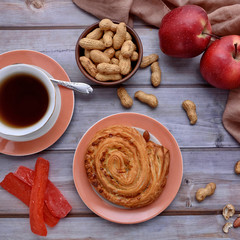 Rustic. Sweet bun. Cup of tea. Peanuts. Red apples. Wood background. Nuts. Fall. Autumnal still life. Top view.