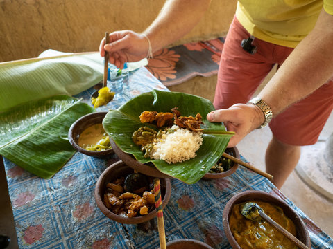 Male hands with rice and curry served in traditional rural kitchen. Eco village Hiriwadunna, Sri Lanka, March 10, 2019.