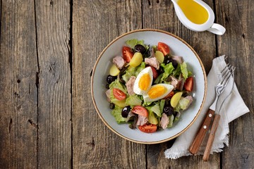 French salad Nicoise with tuna, boiled potatoes, egg, green beans, tomatoes, dried olives, lettuce and anchovies. Top View. 