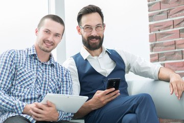 two employees with their gadgets sitting in the office.