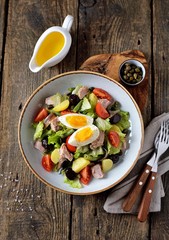 French salad Nicoise with tuna, boiled potatoes, egg, green beans, tomatoes, dried olives, lettuce and anchovies. Top View. 