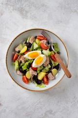 French salad Nicoise with tuna, boiled potatoes, egg, green beans, tomatoes, dried olives, lettuce and anchovies. Top View. 