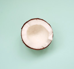 fresh half coconut top view on green background with space for text. minimalism concept