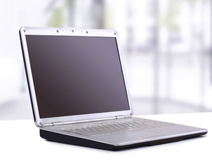 Laptop in the office on the table, with blank screen for text