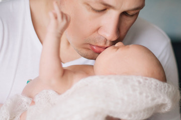Obraz na płótnie Canvas loving father kisses his pretty newborn daughter