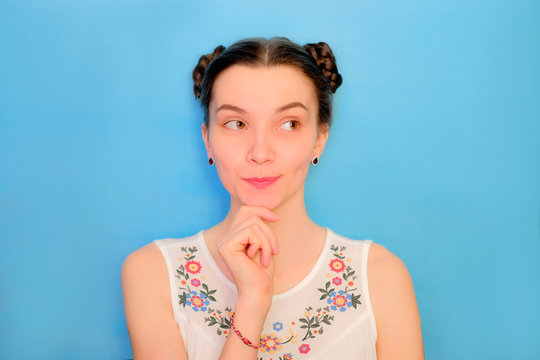 Funny cute girl on a blue studio background. Bright emotional female portrait. Thoughtful face looking away