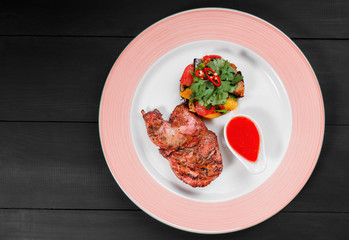 Grilled chicken and salad with grilled vegetables in plate on dark wooden background. Hot Meat Dishes. Top view, flat lay