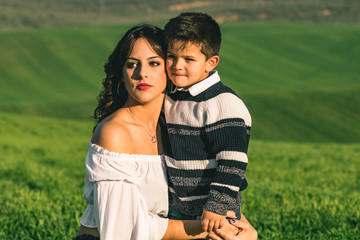Woman and boy on nature over summer field background. Poses on nature