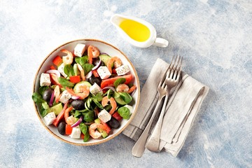 Classic Greek salad from shrimps, tomatoes, cucumbers, red pepper, onion with olives, oregano and feta cheese. Top view. Copy space. 