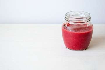 Glass jar with red jam on the table