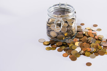 EURO coins in glass jar with colorful coins outside on clear background