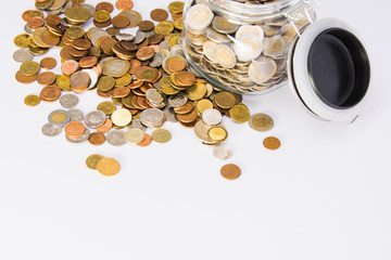 EURO coins in glass jar with colorful coins outside on clear background
