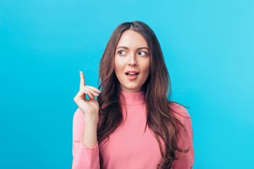 Young beautiful woman having good idea with her finger pointing up isolated on blue background