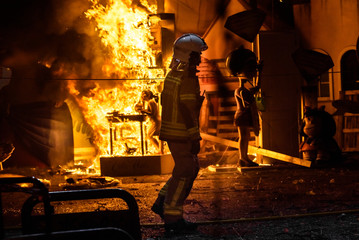 Silhouette of fireman trying to control a fire in a street during a night.