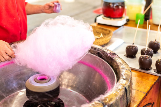 Shopkeeper preparing a Candy Cotton Cloud at a fair for some children.