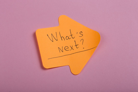 Business, future and motivation concept - orange sticker in the shape of an arrow and text "What's next?" on pink background