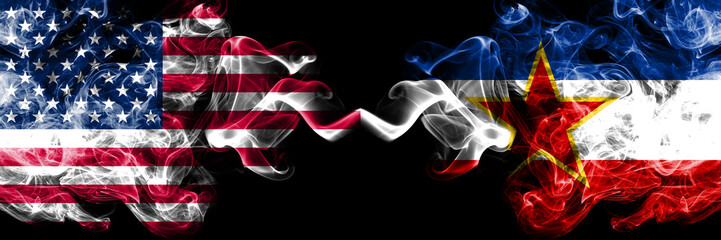 United States of America vs Yugoslavia smoky mystic flags placed side by side. Thick colored silky smoke flags of America and Yugoslavia
