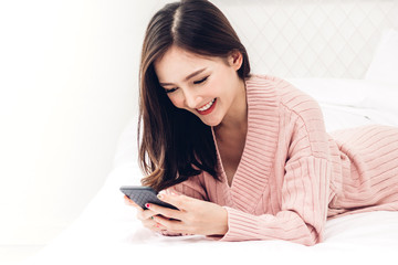 Happy woman relaxing using and talking by smartphone on the bed at home.technology and communication concept