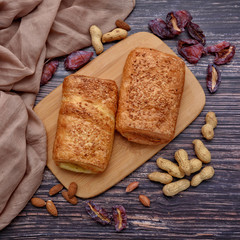 Delicious puff. Sweet bun. Peanuts. Dried fruits. Almonds. Wood background. Dried plums. Fall. Nuts. Autumn still life. Top view.