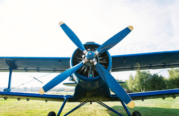 Small plane with propeller on a background of green grass and clear sky.