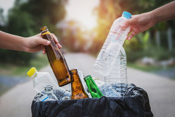 people hand holding garbage bottle plastic and glass putting into recycle bag for cleaning