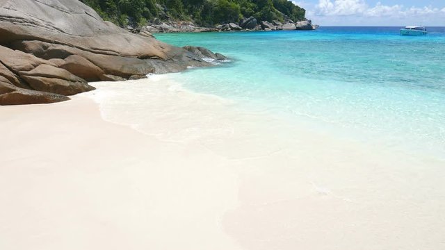 Perfect white sand and crystal clear tropical island, boat anchored in bay