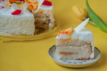Plate with a piece of cake and a tulip flower on a yellow background