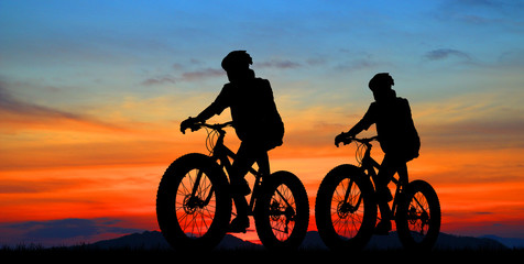 Fototapeta premium Silhouette group friend and bike relaxing on blurry sunset background.