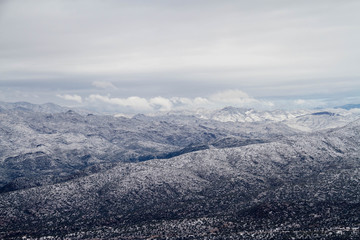 The mountains of Arizona in winter with Snow.  This image has three distinct layers of mountains with dramatic clouds.