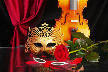 Violin, carnival mask and red rose on black