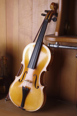 The violin stands near the wooden bar.