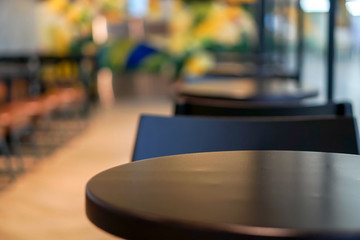 Selective focus of dark brown wooden round table in cafe coffee shop with blurred and background.