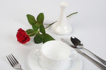 Served table with white dishes, red rose on white background