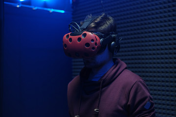 Man plays virtual reality using glasses, gamepad and headset.