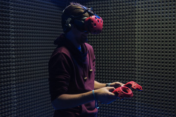 Man plays virtual reality using glasses, gamepad and headset.