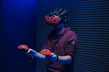 Man plays virtual reality using glasses, gamepad and headset.
