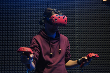 Man plays virtual reality using glasses, gamepad and headset.